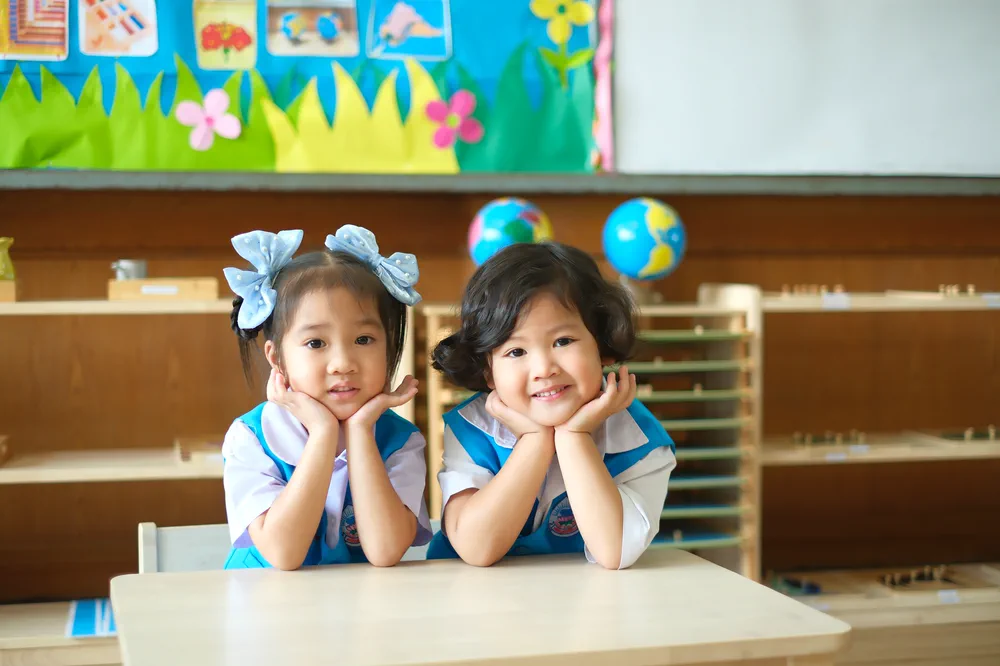เด็กสองคนยิ้มและทำกิจกรรมร่วมกันในห้องเรียนมณีอนุสรณ์ศึกษา
